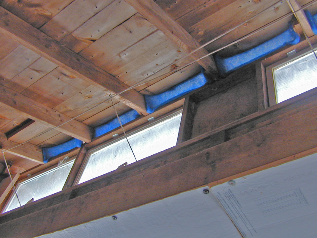 A close view of a backyard chicken coop upper wall vent covered with galvanized hardware cloth and protected by a small wooden awning