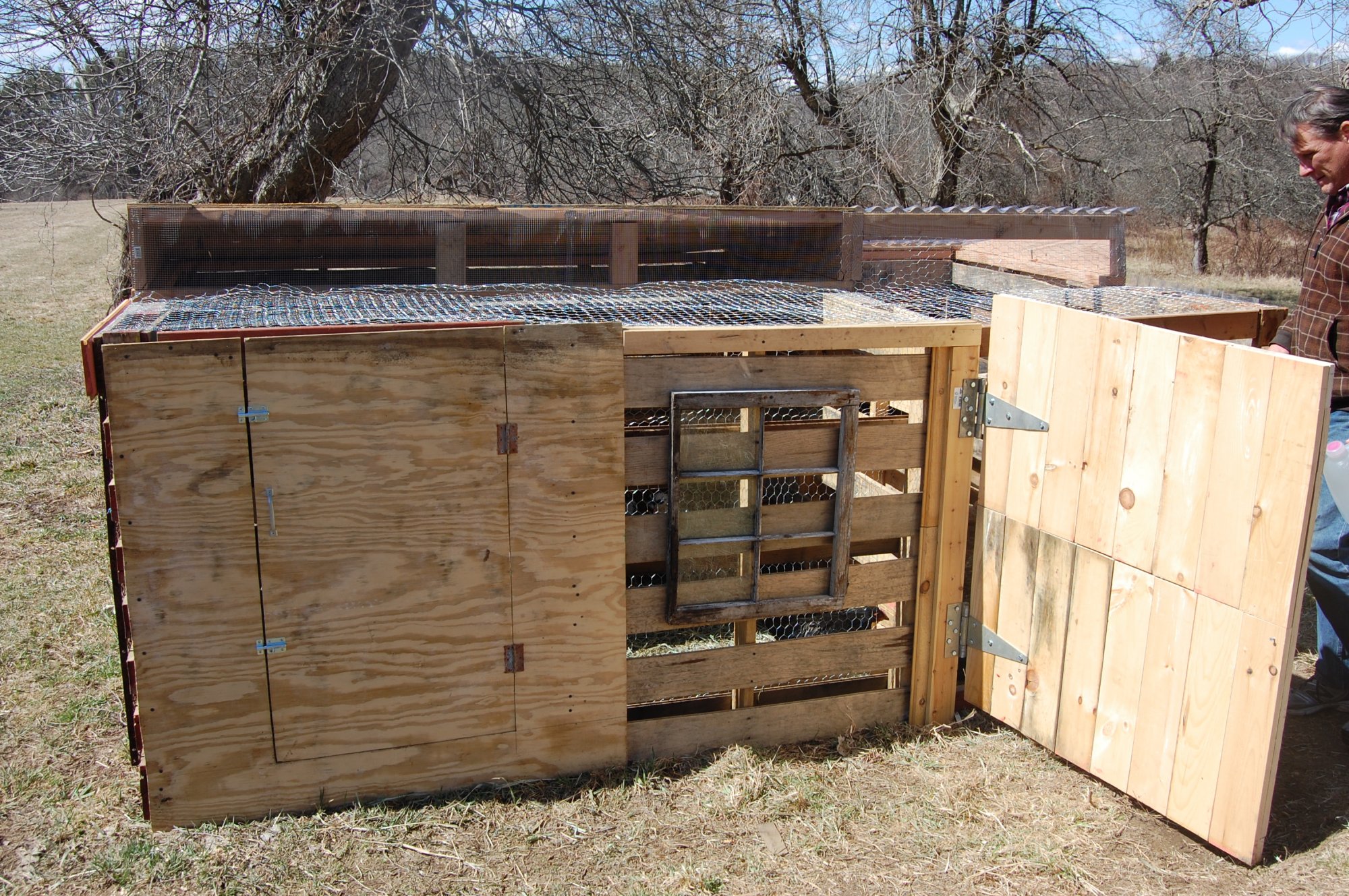 A wooden backyard chicken coop raised on sturdy skids with a sloped roof and wide access door, sitting on a gravel pad